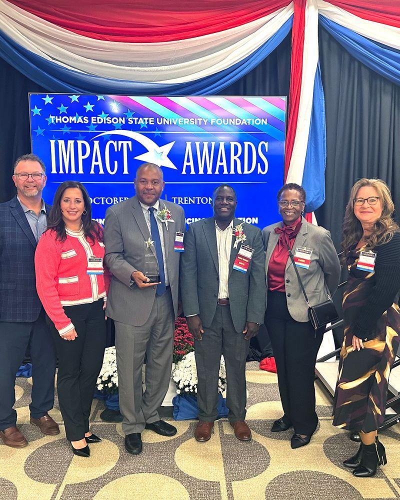 Six people posing with an award