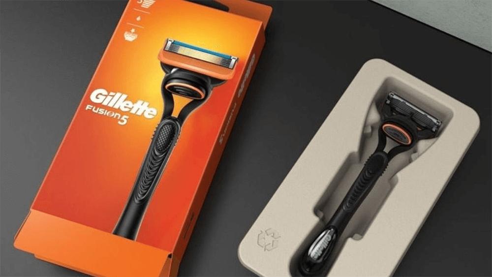 An orange box with Gillette logo and picture on a razor, on the right the product in a cardboard holding box.