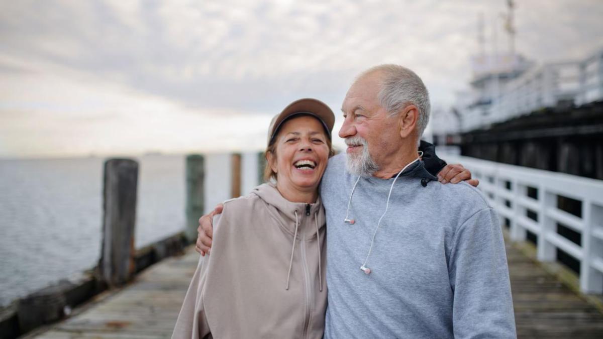 A man and woman shown on a pier in an embrace.