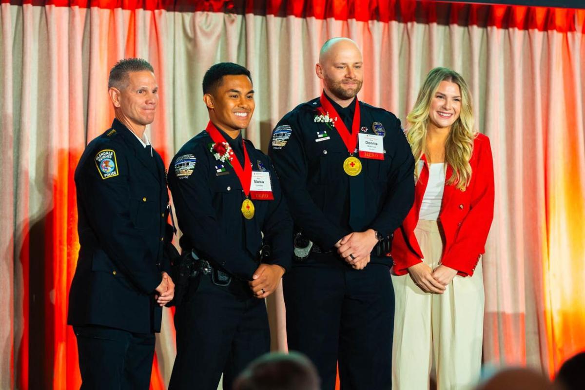 Four people on a stage, three in uniform.