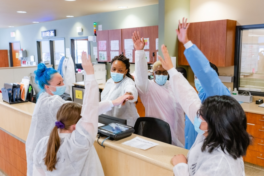 nurses raising their hands at a nursing station