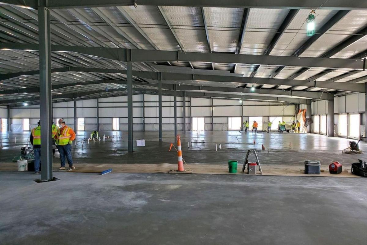 A large open building with concrete floor being poured and set.