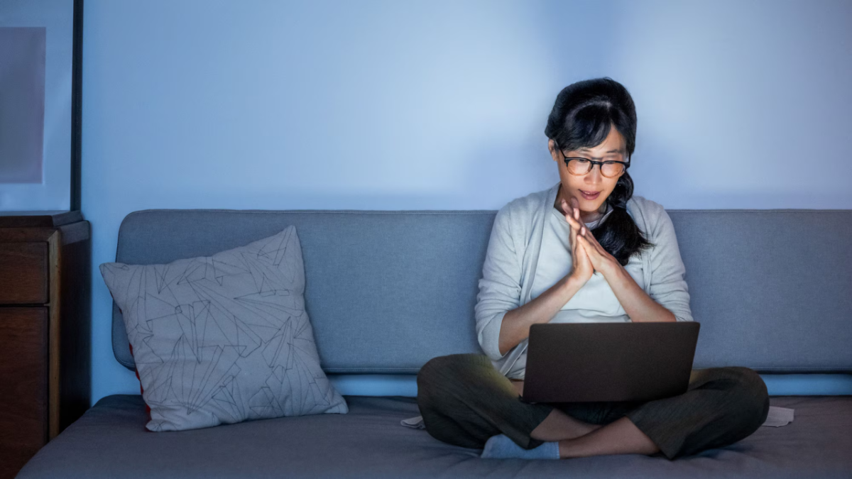 Woman sitting on a couch with open laptop