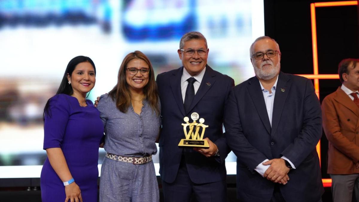 Four people posing, one holding an award