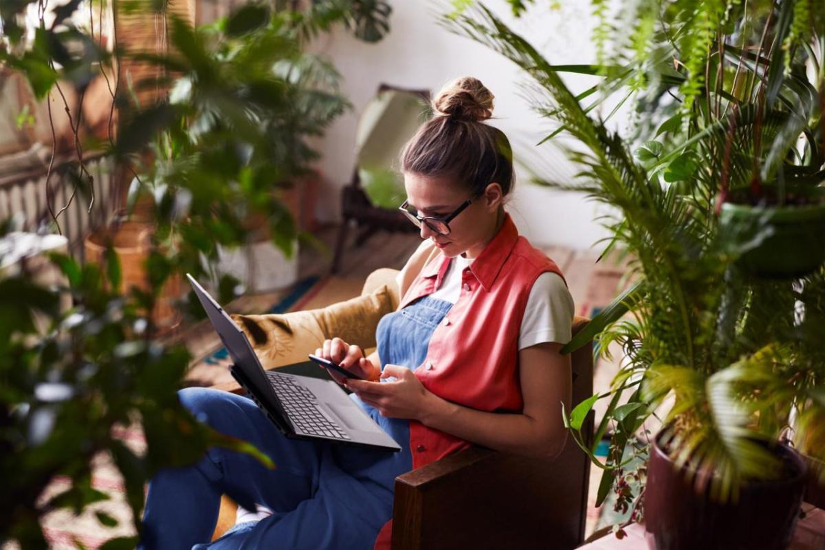 Woman working on laptop surrounded by houseplants