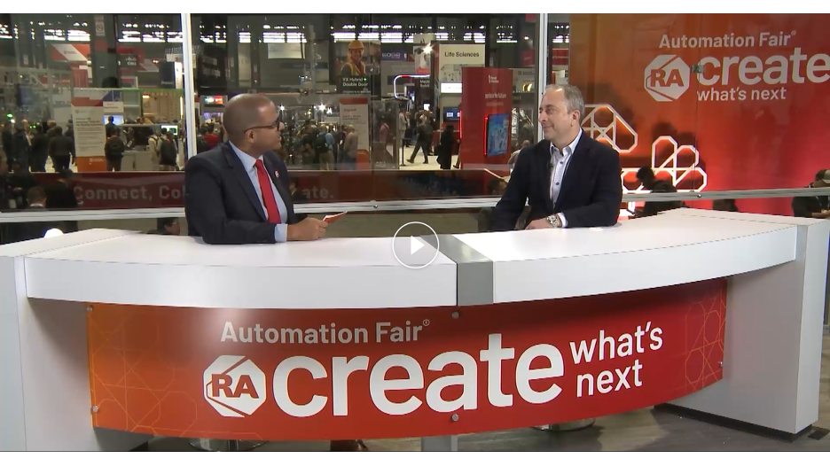 Two people talking behind a desk that reads "Automation Fair: Create what's next"