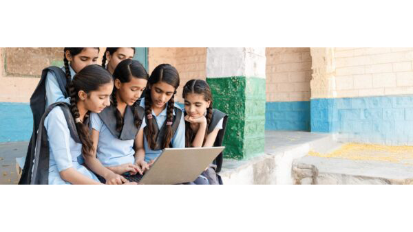 A group of young students gathered around a laptop
