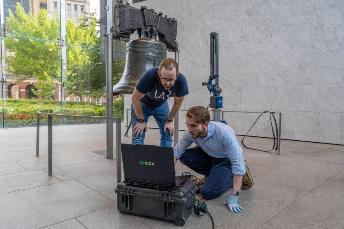 two people working next to the liberty bell