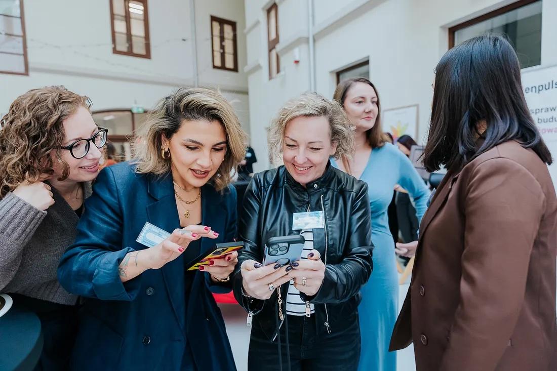Women dressed in business attire eagerly looking at phones
