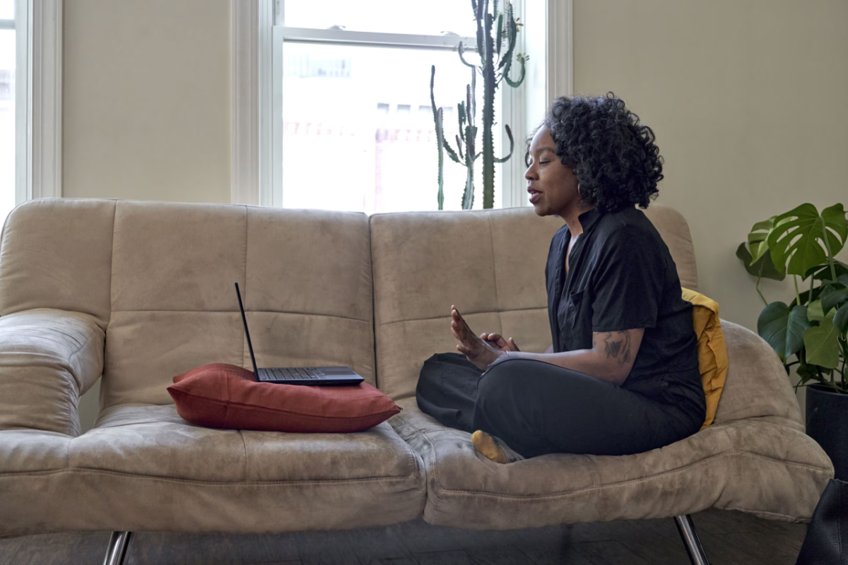 A woman sitting on a couch, in an online meeting