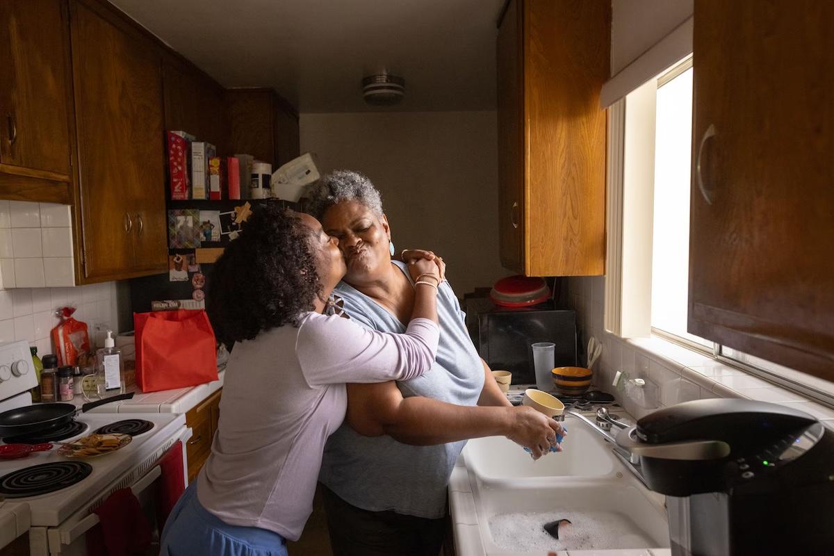 Two women hugging in a kitchen.