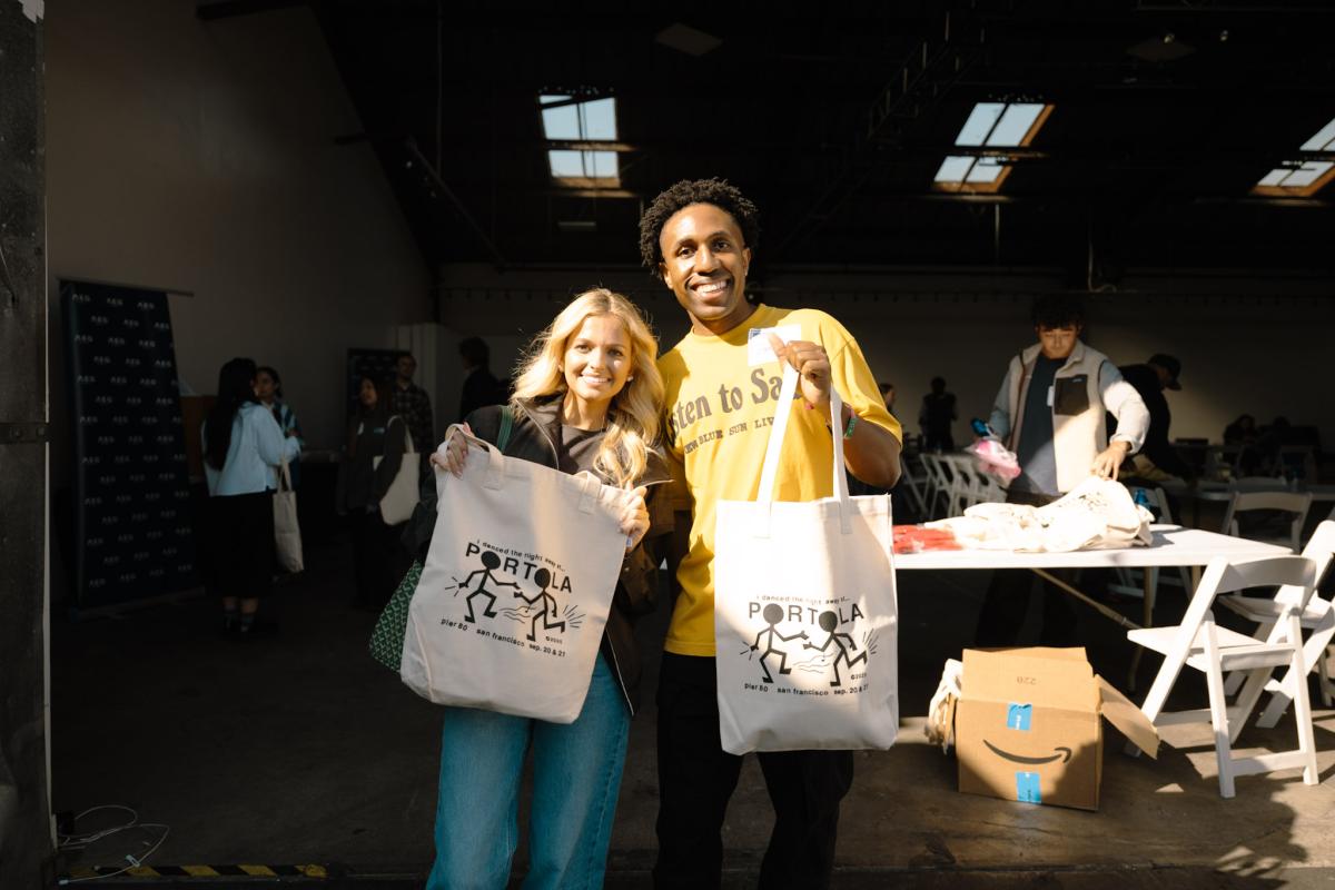 Two event participants pose with Portola-branded tote bags during the College Connection Program.