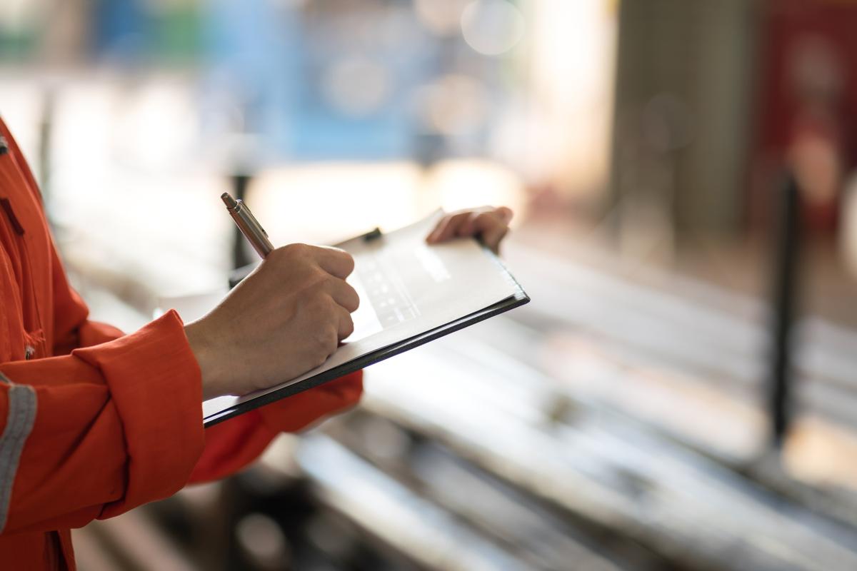 Worker in safety orange writing on a tablet