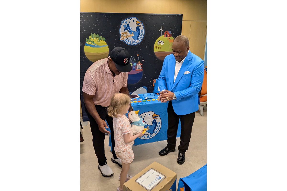 Former professional baseball and football player Brian Jordan (l) and Aflac Incorporated and Aflac U.S. President Virgil Miller (r) hand a My Special Aflac Duck to Leighton, a six year old patient at SSM Health Cardinal Glennon Children's Hospital in St. Louis.