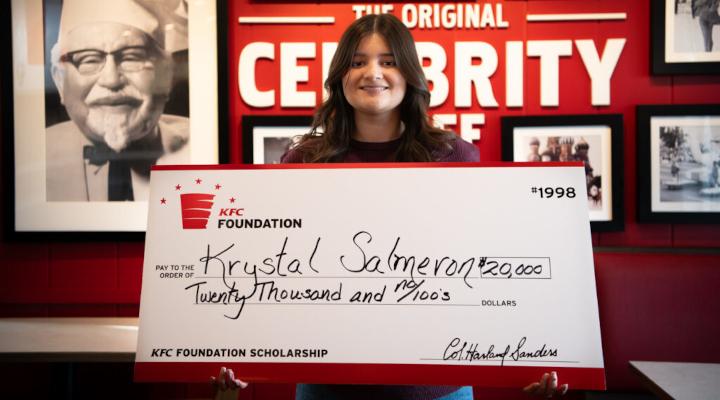 Scholarship recipient holding up check