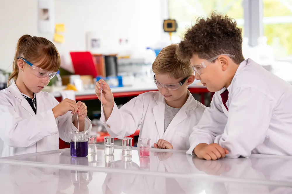 Young students in white coats doing lab experiments