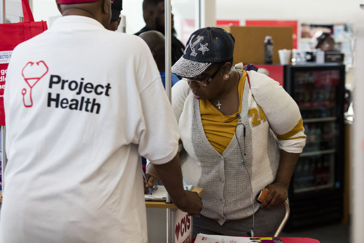 Person wearing Project Health shirt helps someone to sign up