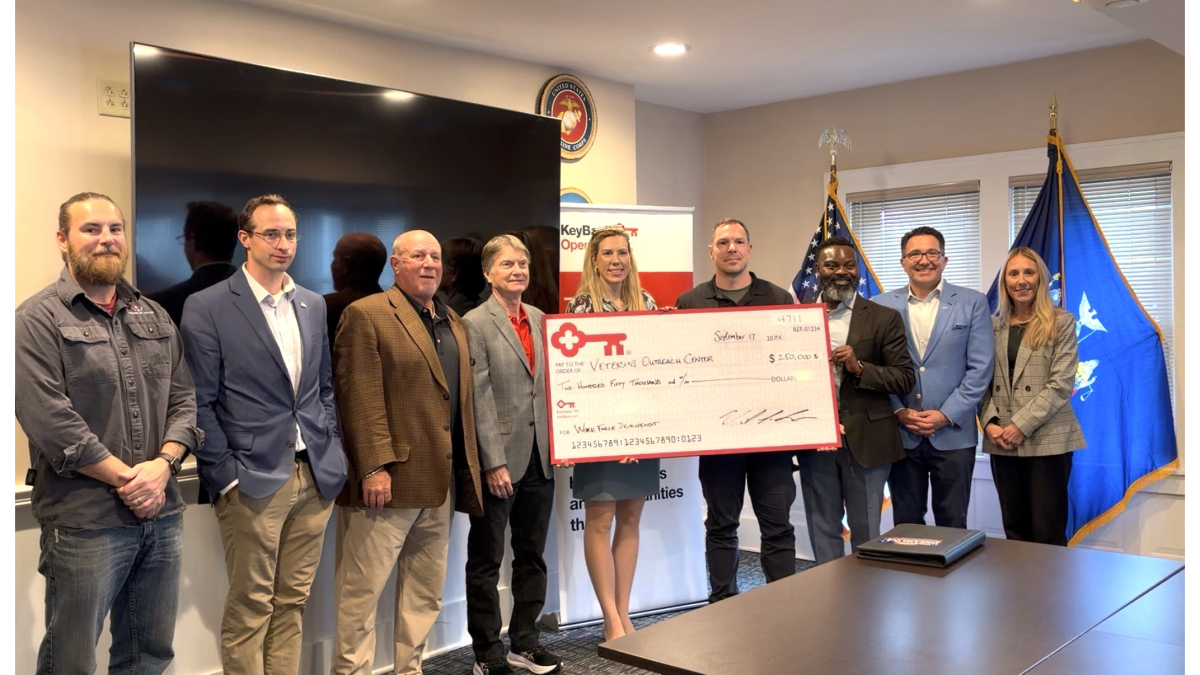 A small group standing together, holding an oversized check from KeyBank