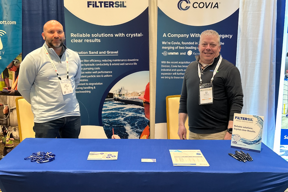 Mike Mongell and Joel Eaton standing behind a Covia desk at an event