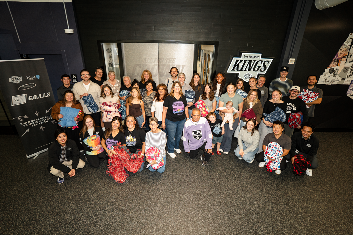 Volunteers pose for group photo in front of the Kings office with blankets made 