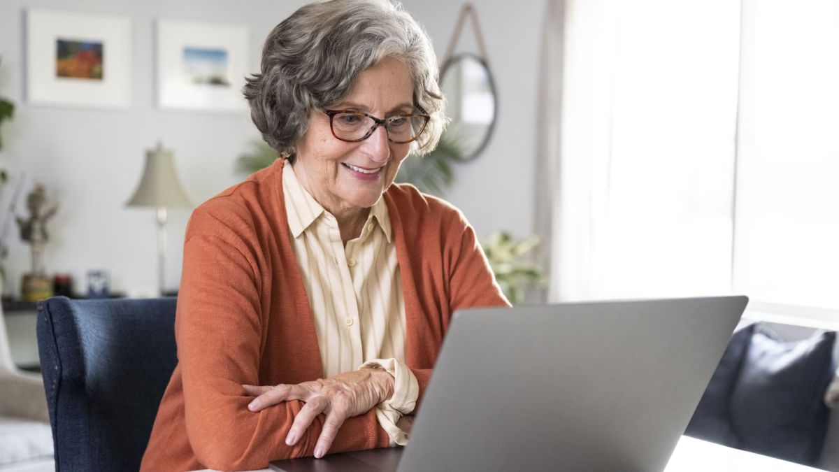 person smiling while looking at a laptop