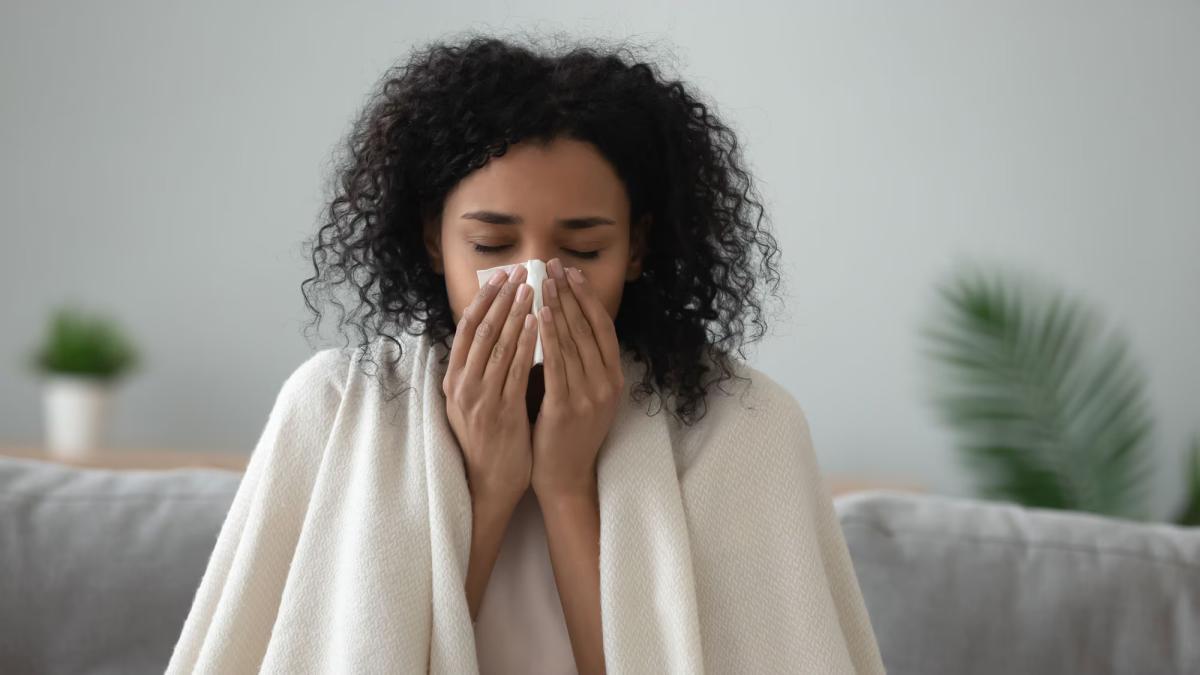 A person shown with a tissue and a blanket over their shoulders.