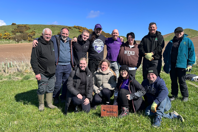 12 people posing together on a hillside