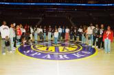 Group of students and professionals standing on the Los Angeles Sparks basketball court for a photo inside Crypto.com Arena.