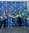 People posing with prop saws that read "I BUILT A BED TODAY"