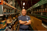 A person standing in a warehouse surrounded by shelves and boxes