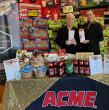 A person and person standing next to a table with food items