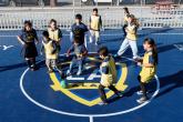 Children wearing LA Galaxy jerseys and pinnies play soccer around a ball on a branded mini-pitch court.