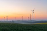 Wind turbines in a field with a sunset in the background