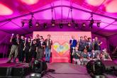 People posing on a stage, holding up a heart
