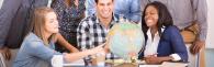 3 people having a discussion around a globe