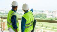 Two workers looking out at a project wearing protective gear.