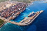 Aerial view of DP World’s Port of Caucedo in the Dominican Republic, showing container ships docked at the terminal, cranes loading cargo, and stacked shipping containers along the turquoise Caribbean coastline.