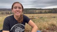 A young person shown in a field on a farm.