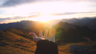 hand reaching out looking at sunrise