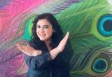 Woman in front of a colorful mural crossing her arms
