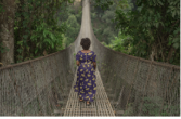 woman walking alone across a long bridge