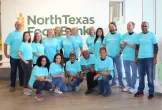 Calvin and a group of others in matching blue "Bread Financial" tshirts, posing in front of a wall with "North Texas Food Bank" on it.