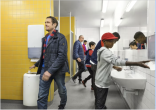People in a public bathroom using Tork's new hygiene products to wash their hands
