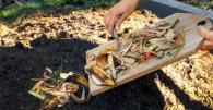 Someone scraping food waste off a cutting board into a compost pile