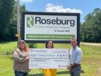 3 people holding a big check in front of a Roseburg sign