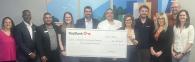 Representatives from KeyBank and Enterprise Community Partners shown with a grant check for $300,000.