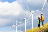 Two workers viewing windmills on a hill.