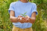 Young woman holding a small plant in her hands.