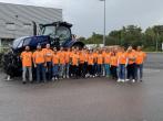 Group photo of participants in orange shirts in front of large tractor
