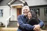 Young couple hugging in front of their new home.